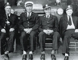 Fire Station crew members sit in front of a fire truck